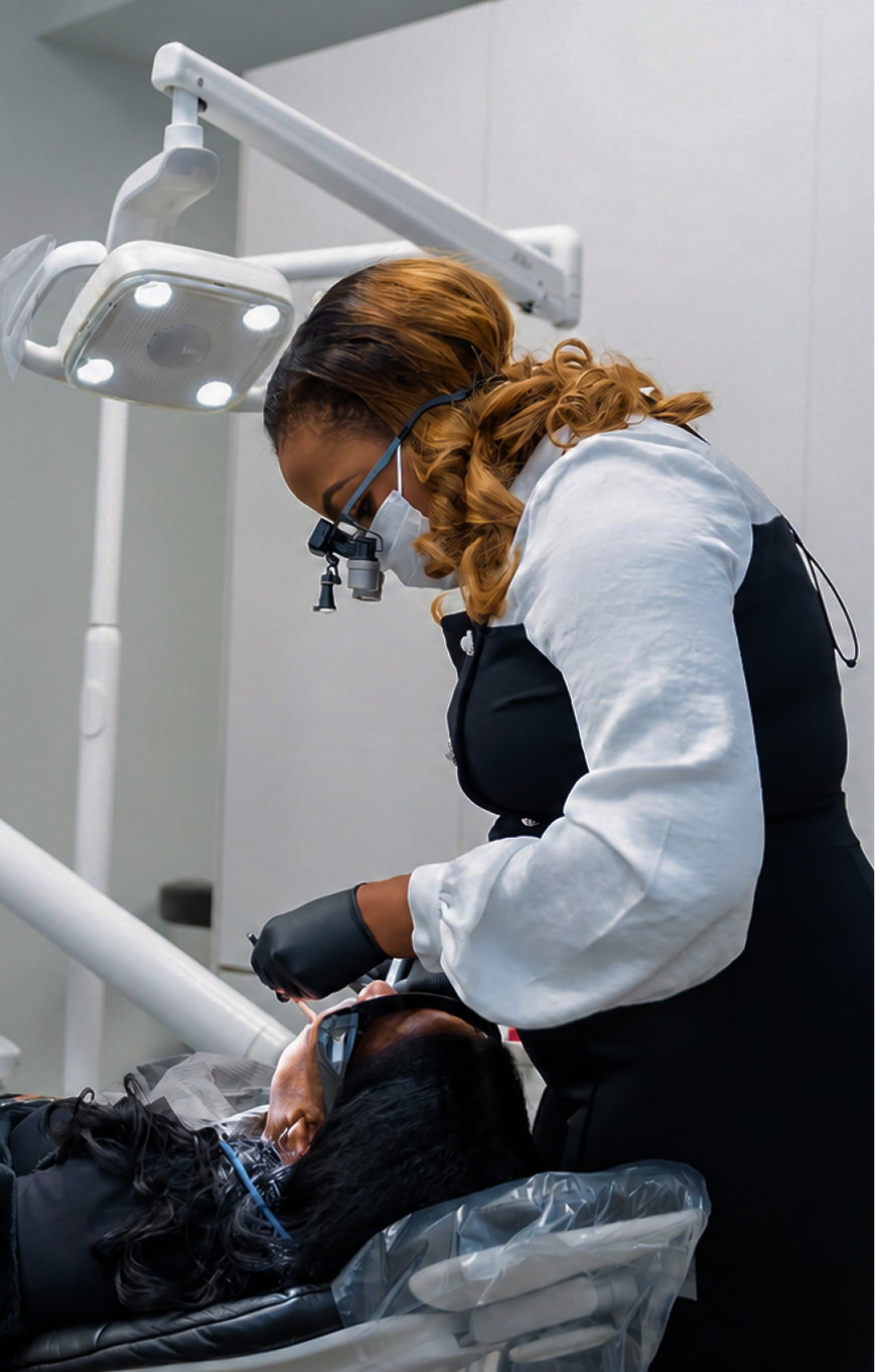 Dentist examining a patient's teeth under overhead surgical light in treatment room