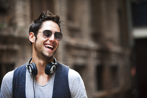 Man wearing sunglasses and headphones smiling, displaying bright white teeth