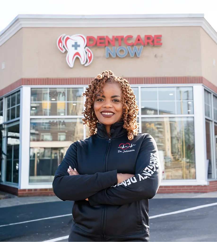 Dr. Johnson smiling with arms crossed in front of Dentcare Now office storefront