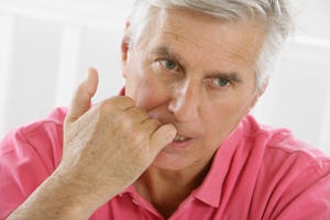 Man in pink shirt biting his fingernails