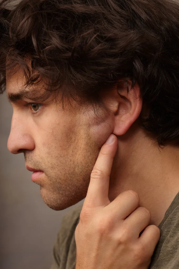 Man in profile with hand touching his jaw, demonstrating a lipoma on the neck area