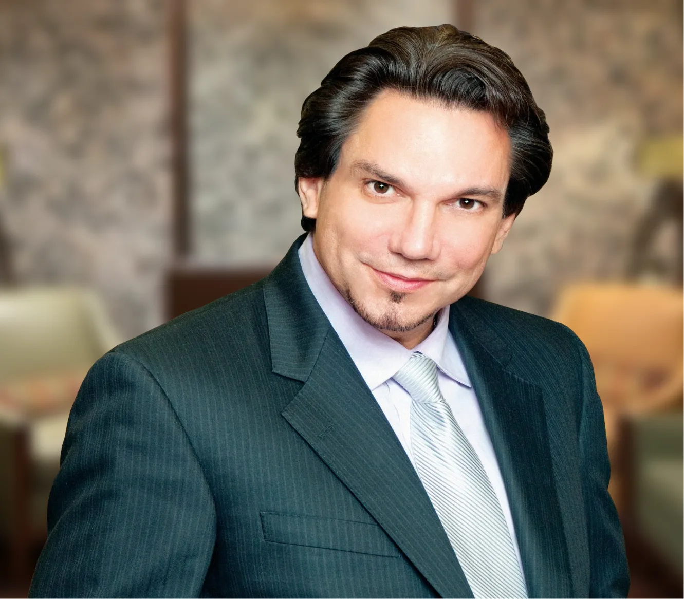Professional portrait of a man in a dark pinstriped suit and light blue shirt