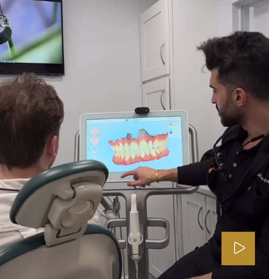 Dentist pointing to digital smile design software showing teeth visualization on screen with patient in treatment chair