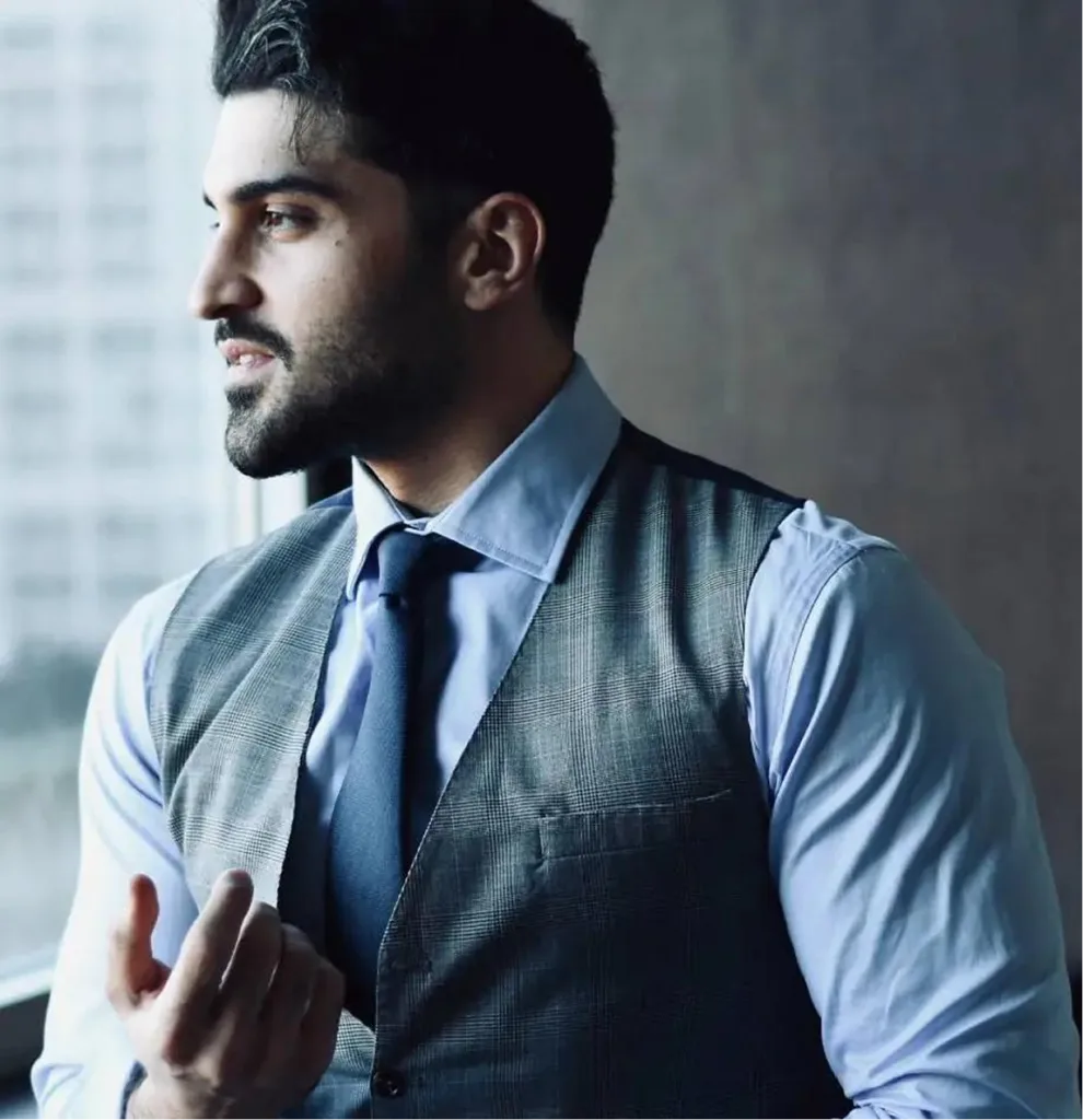 Man in professional attire with light blue shirt and dark tie looking to the side