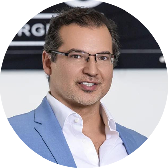 Man wearing glasses and blue blazer smiling at camera