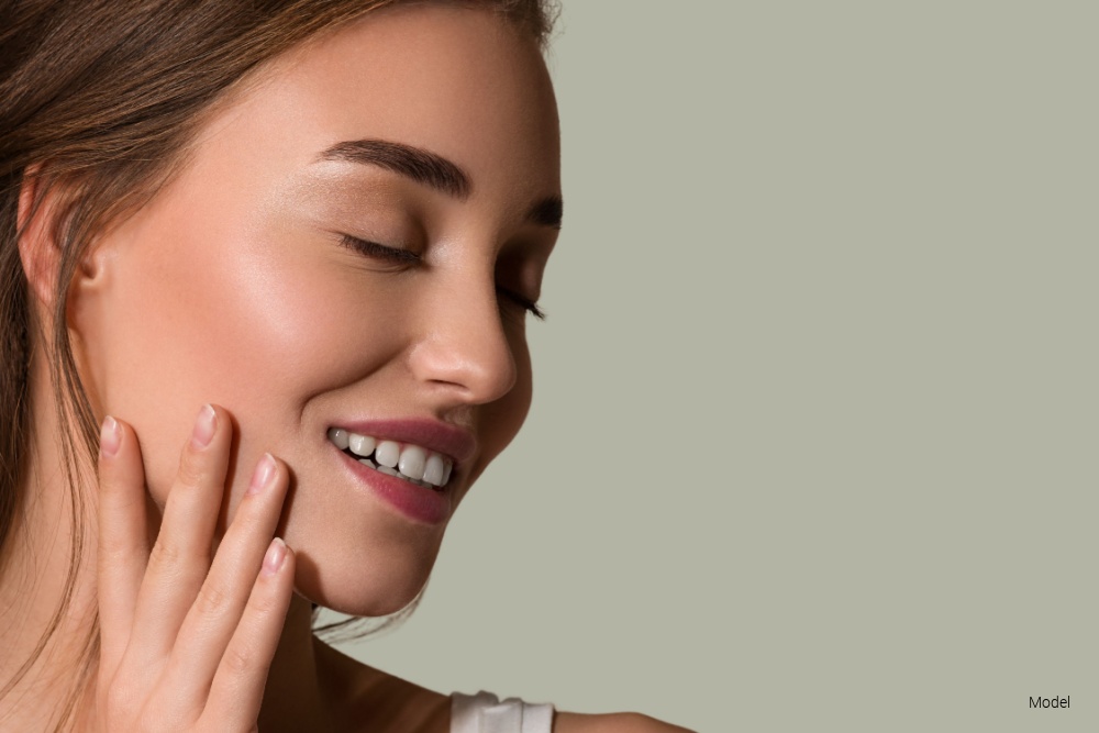Woman touching her face with hand, smiling in profile
