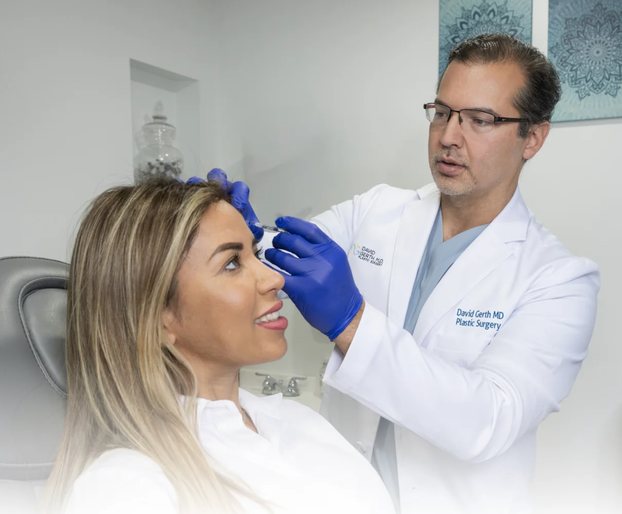 Dr. David Gerth examining a patient's face while wearing blue gloves during a dermal filler consultation