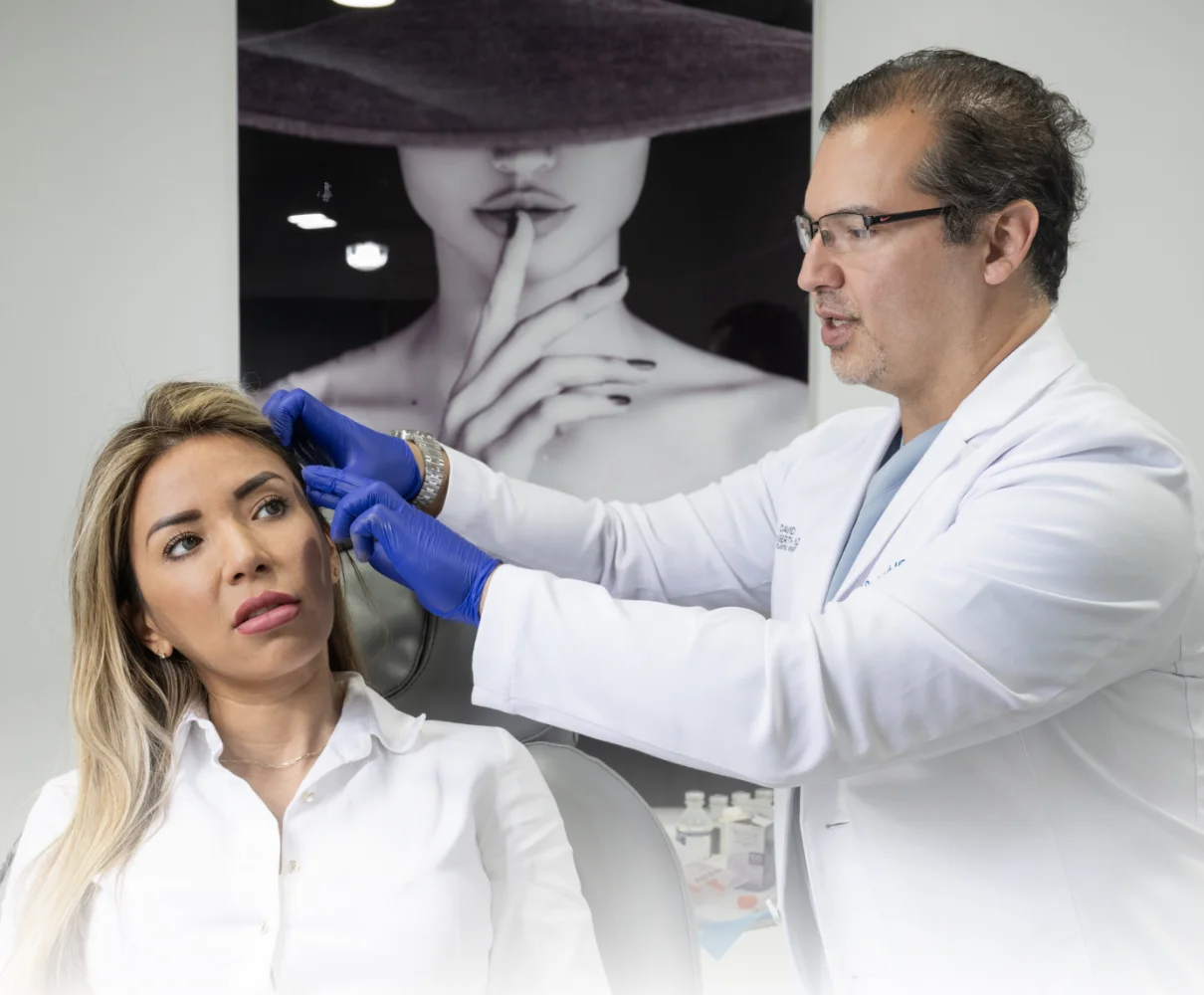 Plastic surgeon in white coat and blue gloves examining patient's face during consultation