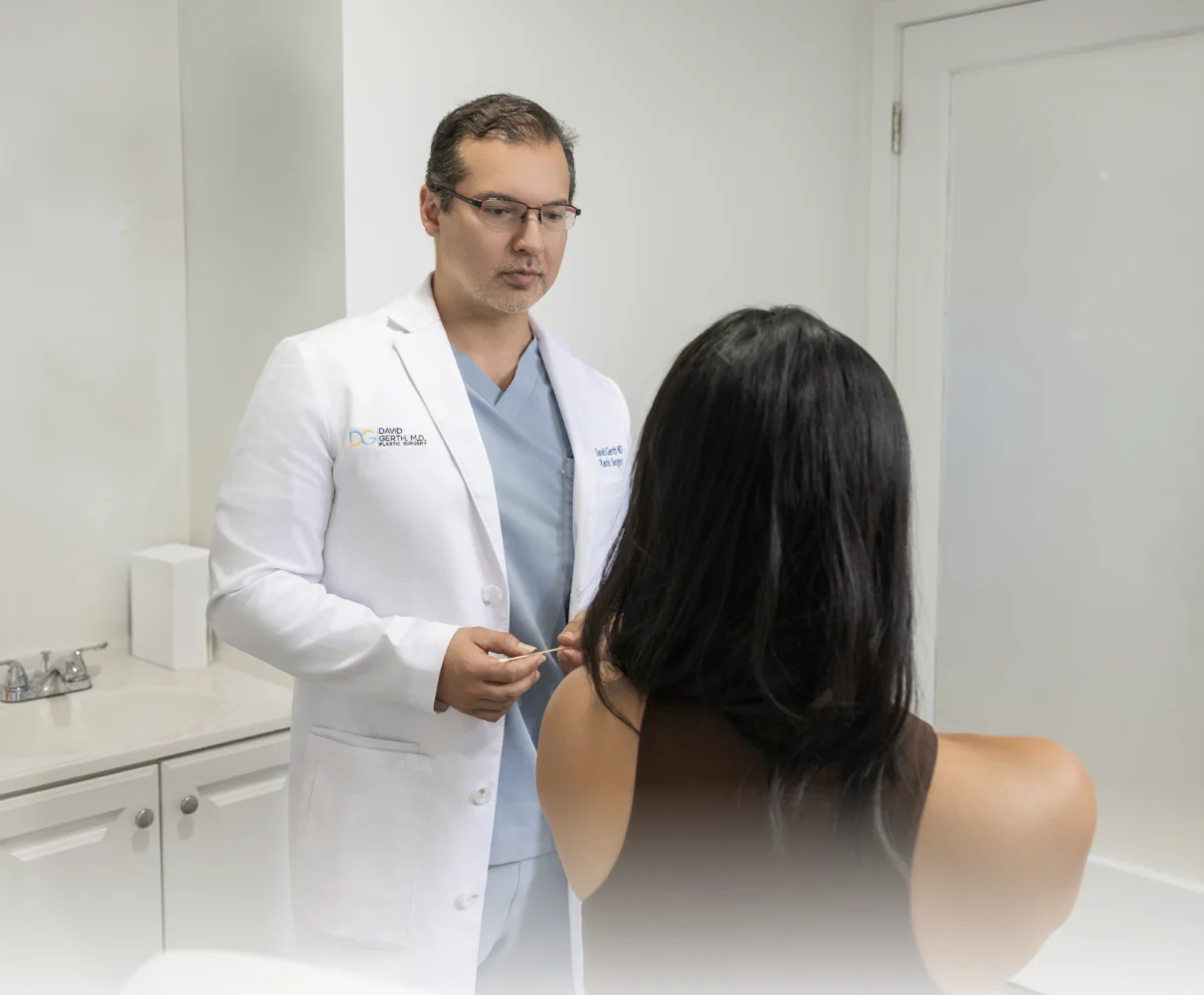 Physician in white coat and blue scrubs consulting with patient about facial treatment in clinical setting