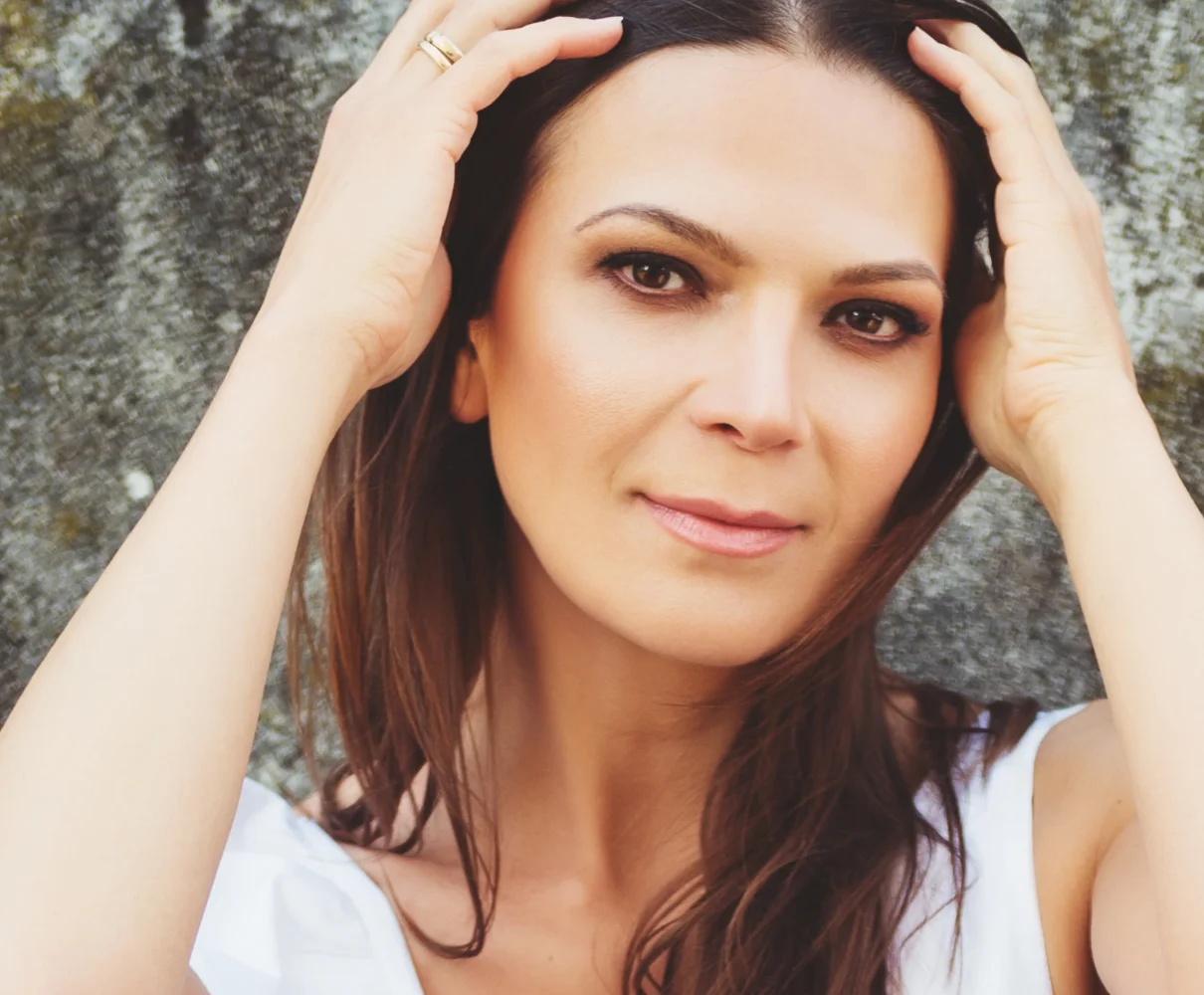 Woman with hands in her hair showing defined facial contours and skin texture