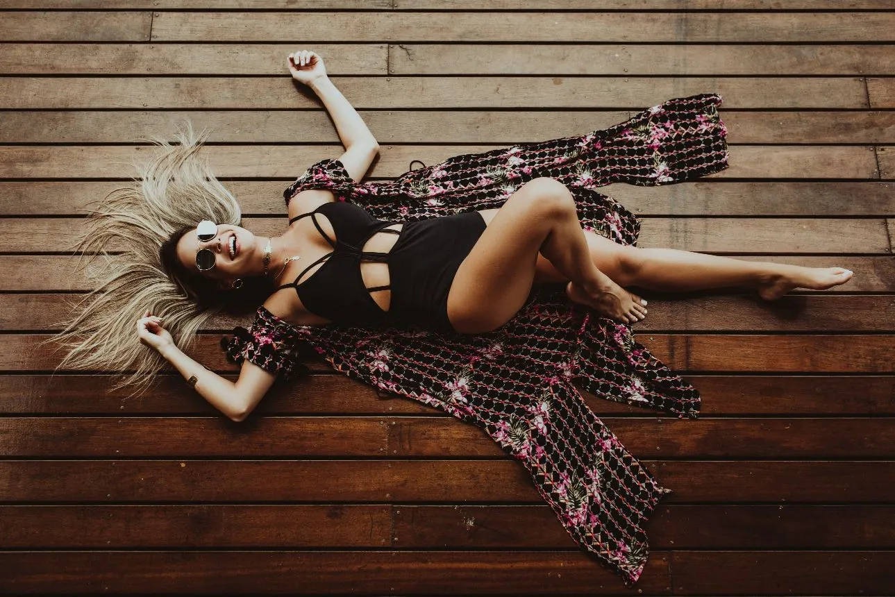 Woman in a black swimsuit relaxing on a wooden deck - body contouring results for summer