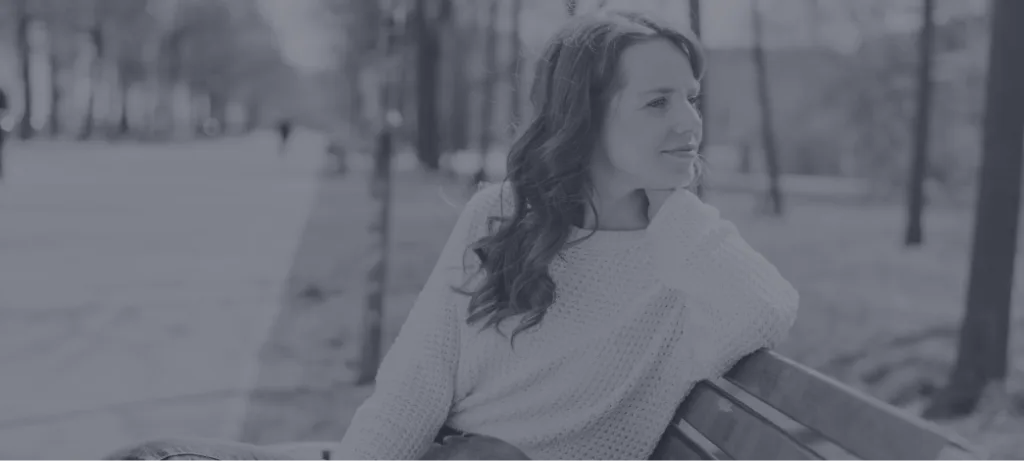 Woman sitting on a bench outdoors looking contemplatively to the side