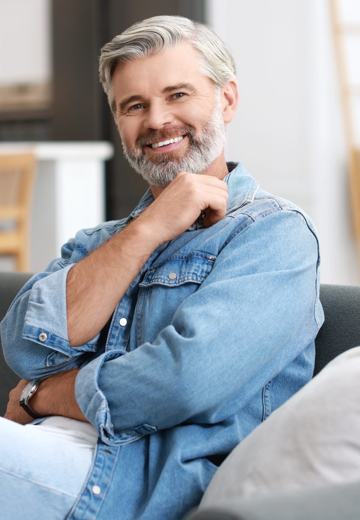 Mature man smiling with hand near face in casual denim shirt