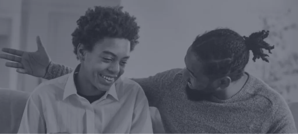 Two people laughing together indoors on a couch