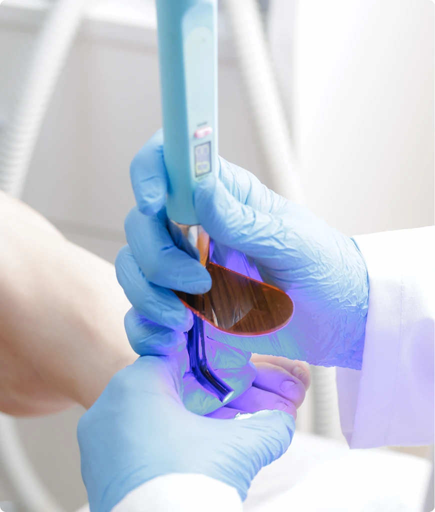 Gloved hands holding medical diagnostic device with purple light
