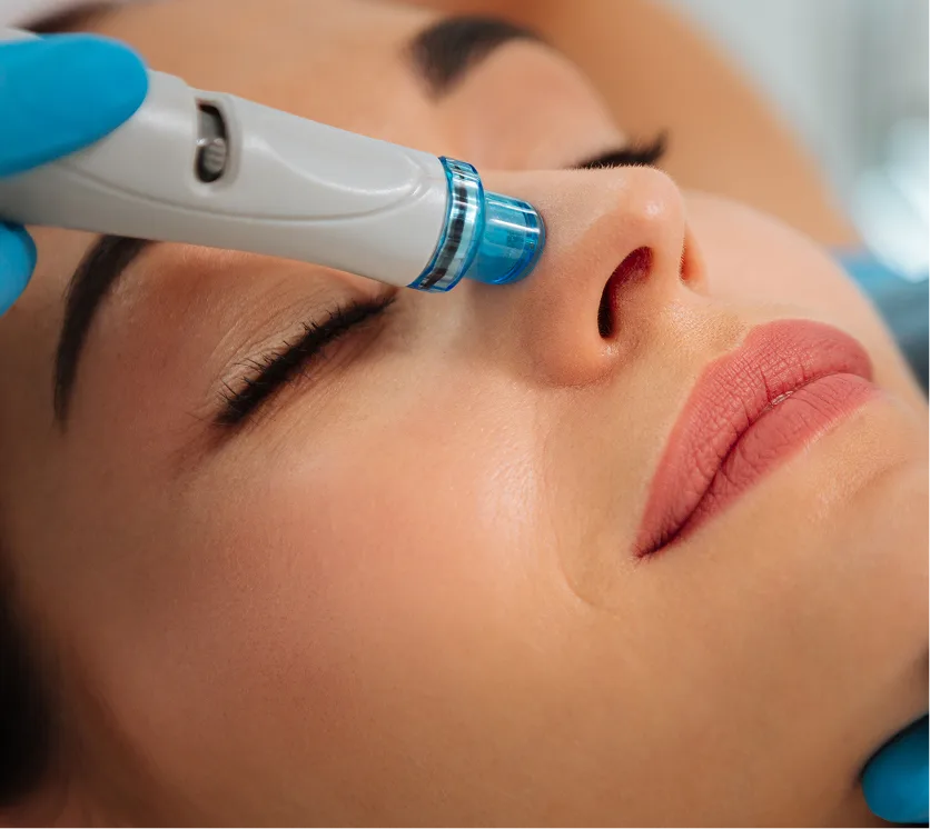 Clinician applying HydraFacial device to patient's cheek during facial treatment