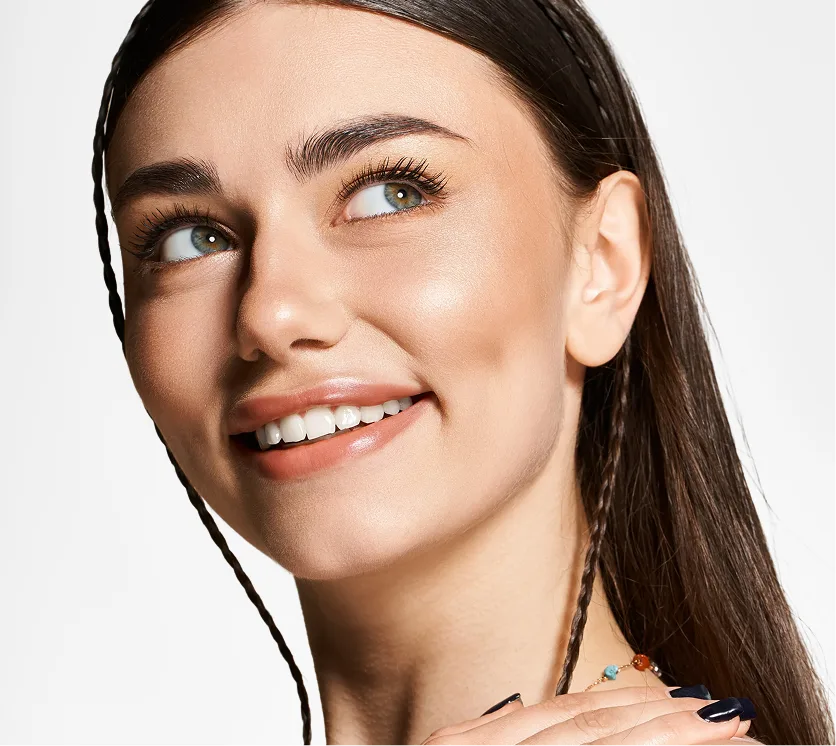 Woman with radiant skin and defined eyebrows smiling at camera