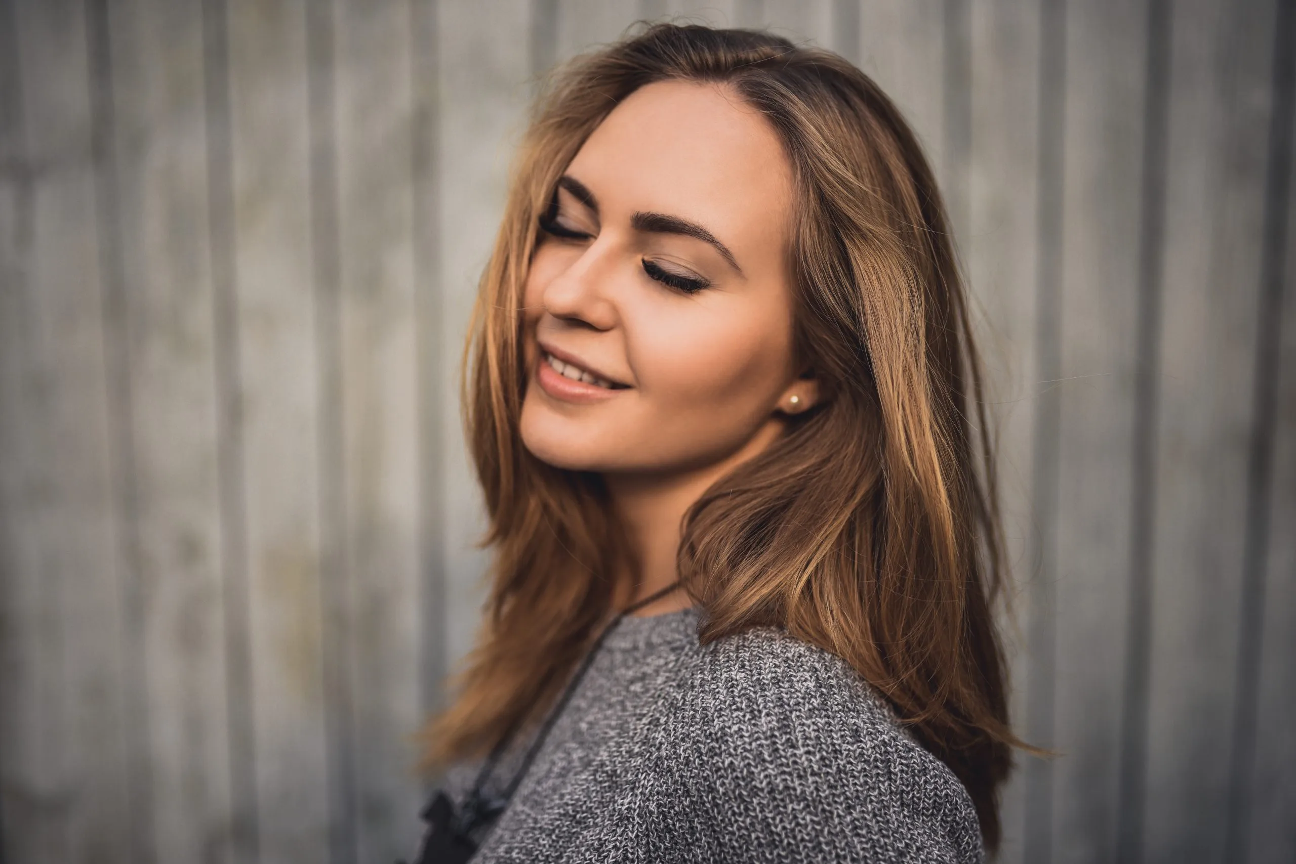 Woman with long brown hair smiling while looking over shoulder