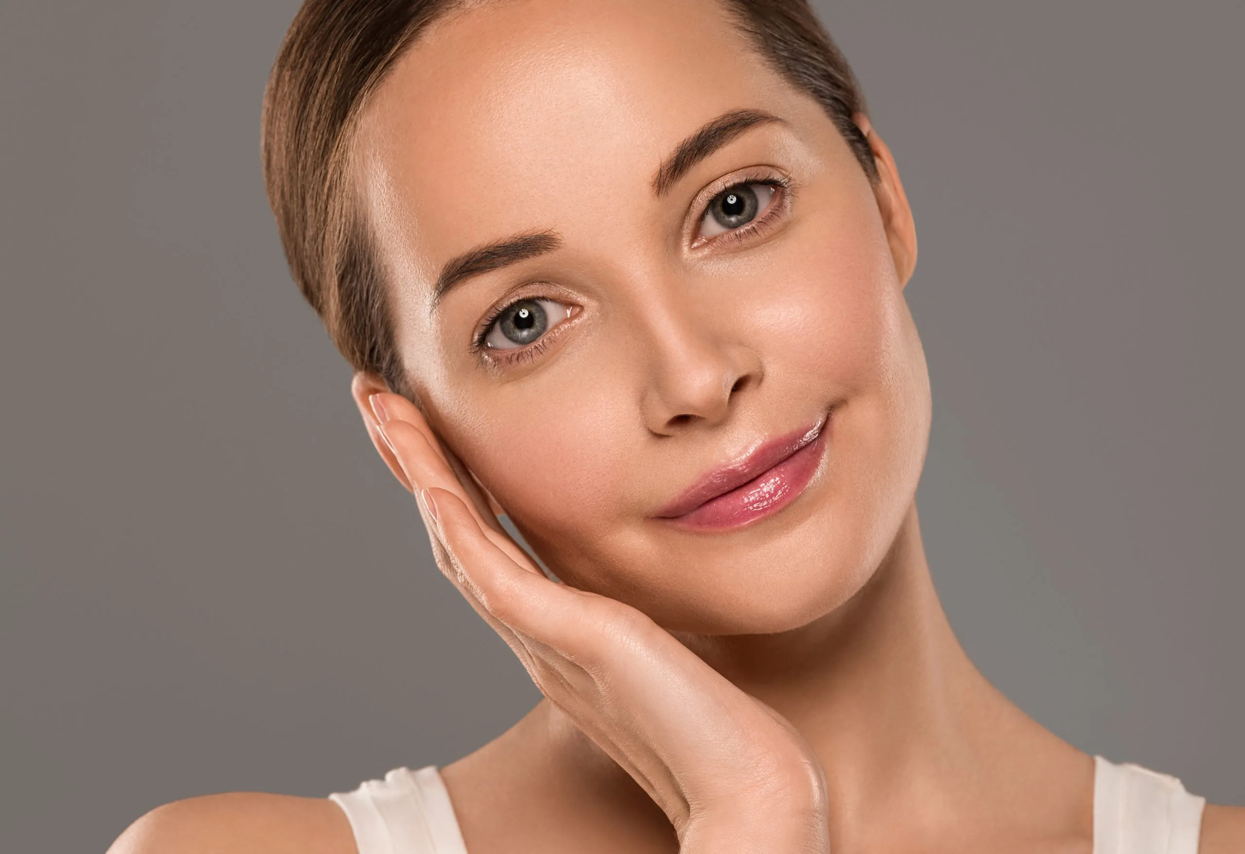 Woman touching her cheek to camera, displaying smooth facial skin