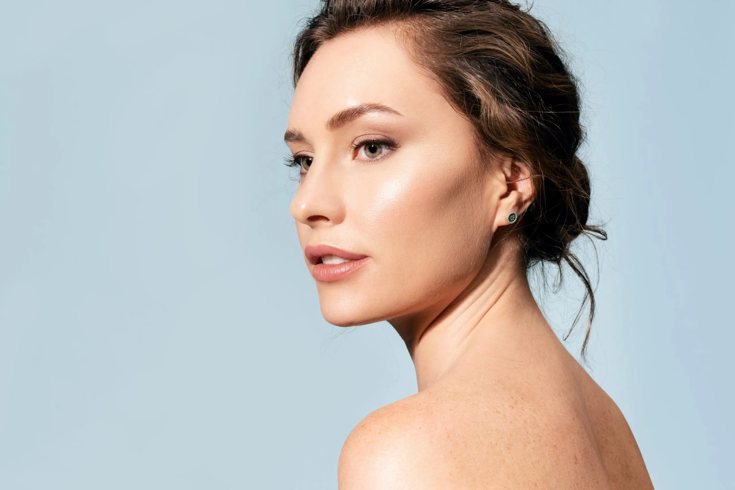 Woman in profile with bare shoulders against blue background