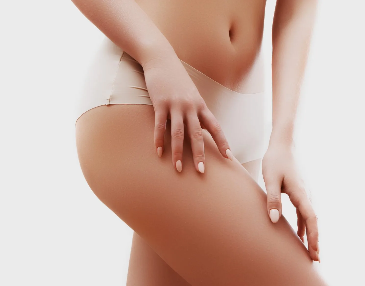Woman in white swimsuit touching her hip and buttock area from behind