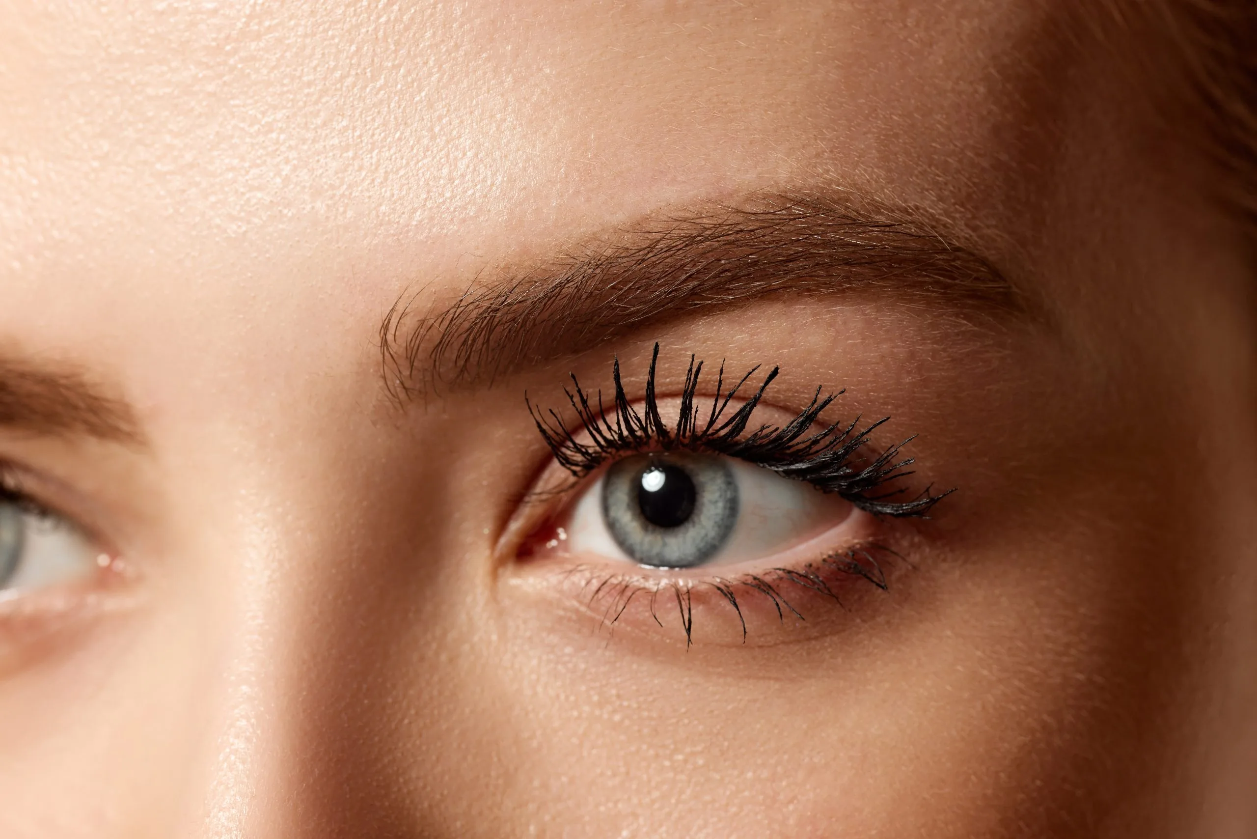 Close-up of woman's eye with full lashes and defined brow