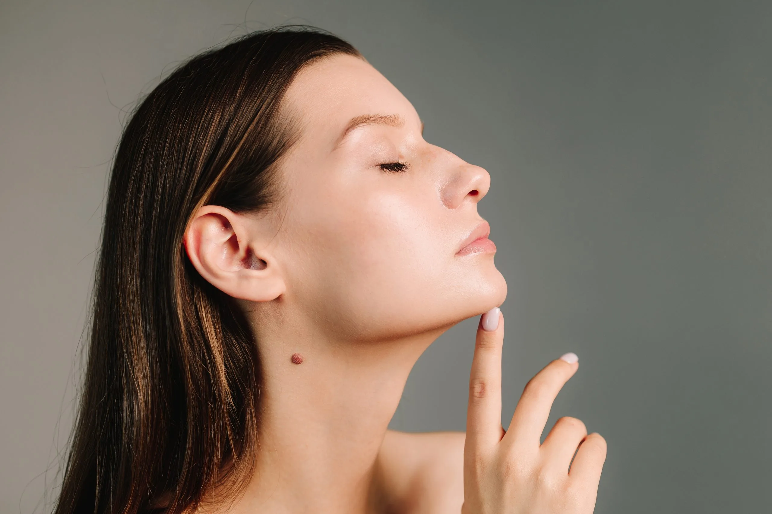 Woman in profile with eyes closed, touching her chin and jawline area