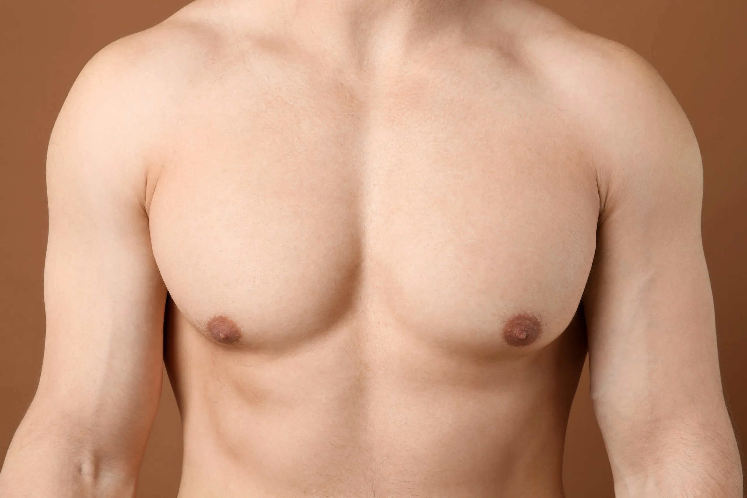 Shirtless man standing facing forward against tan background