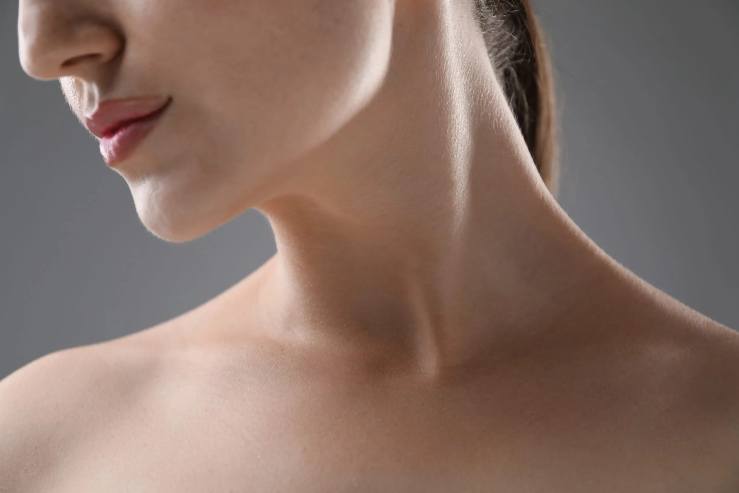 Woman's profile showing defined jawline and smooth neck against gray background