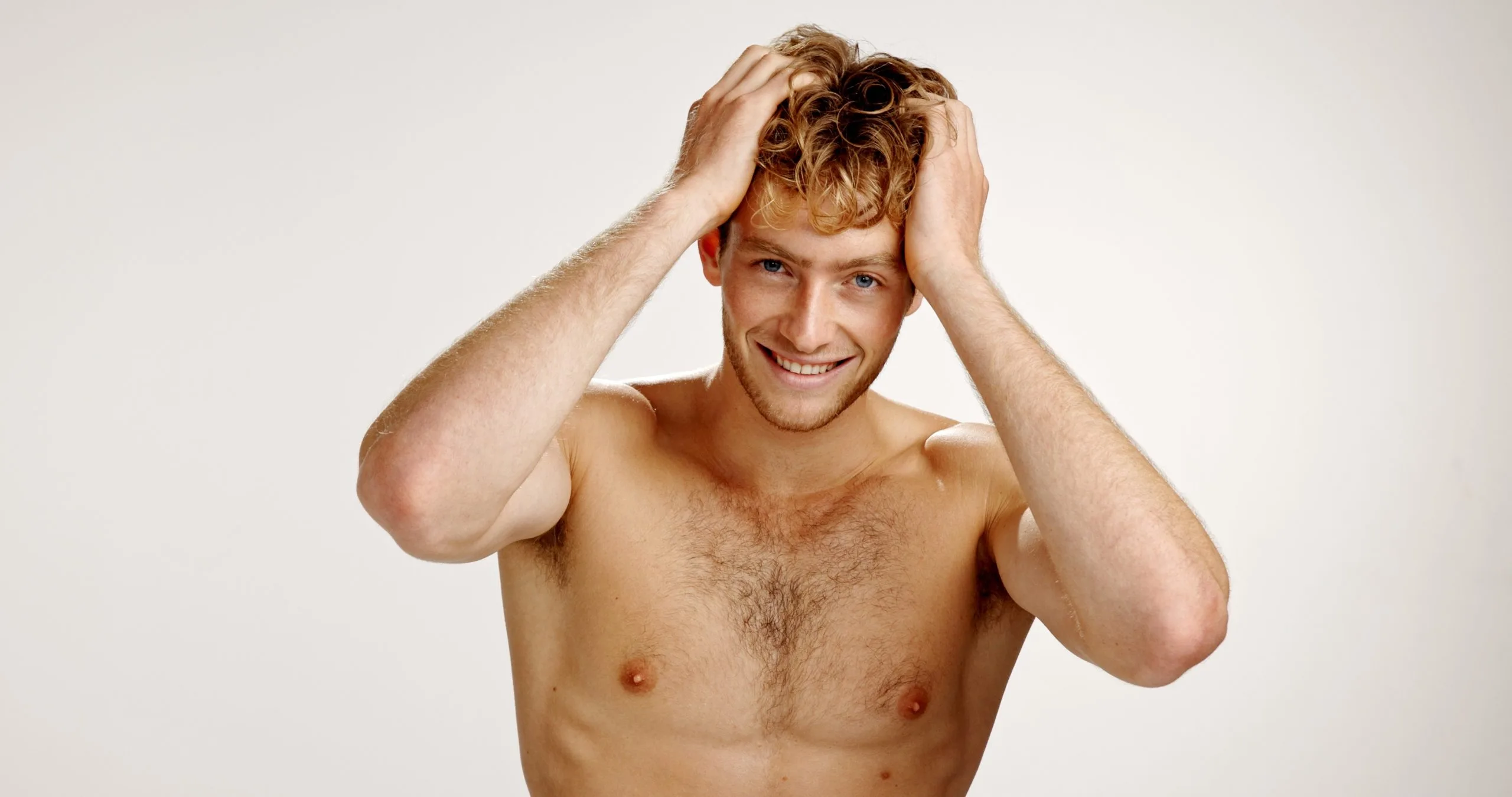 Shirtless man with curly hair running hands through his hair