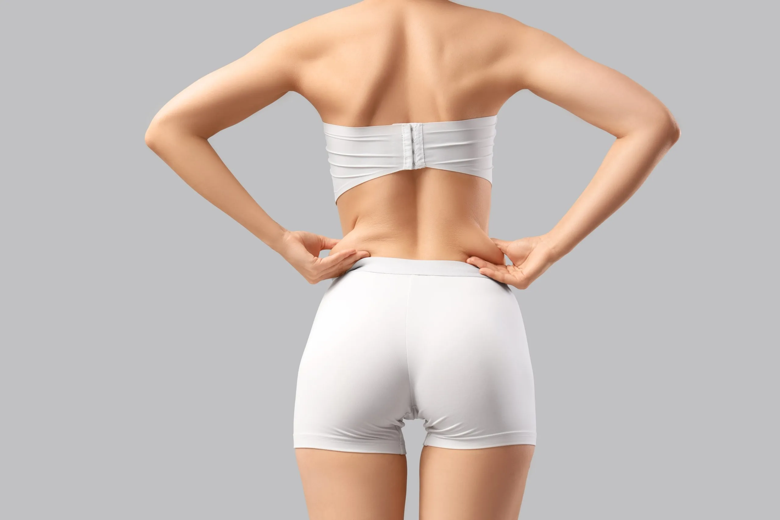 Woman from behind wearing white undergarments displaying torso and hip contours
