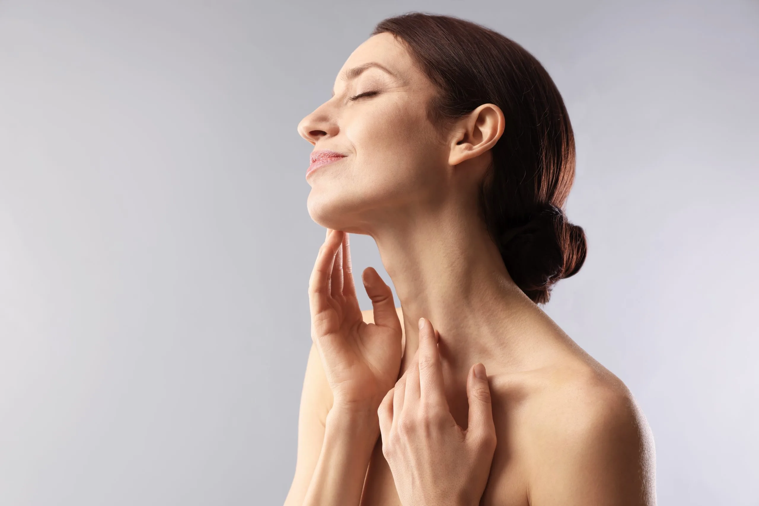 Woman with eyes closed touching her chin and neck area