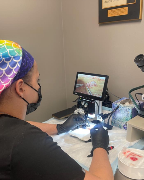 Practitioner in colorful headwrap performing injectable treatment with digital imaging display