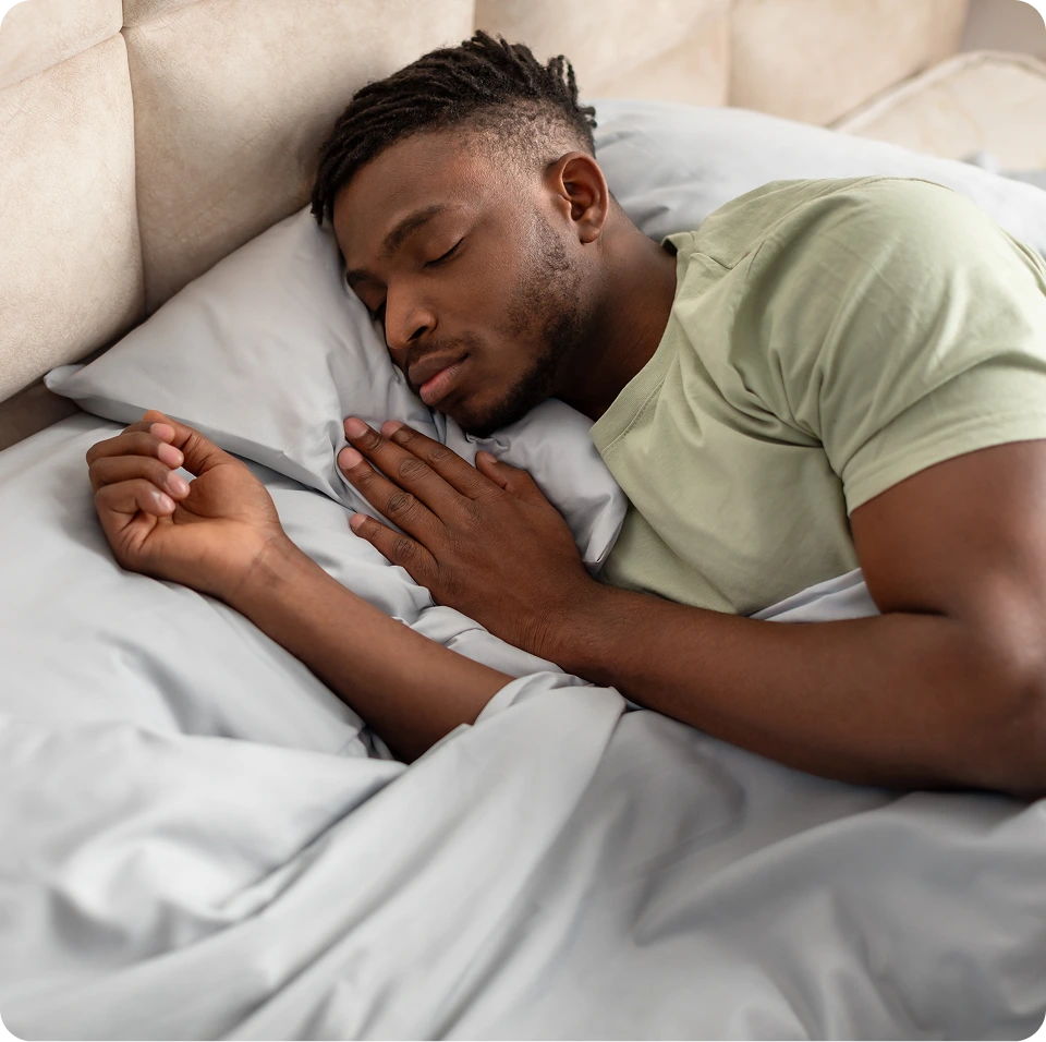 Man sleeping peacefully in bed with white pillows and sheets