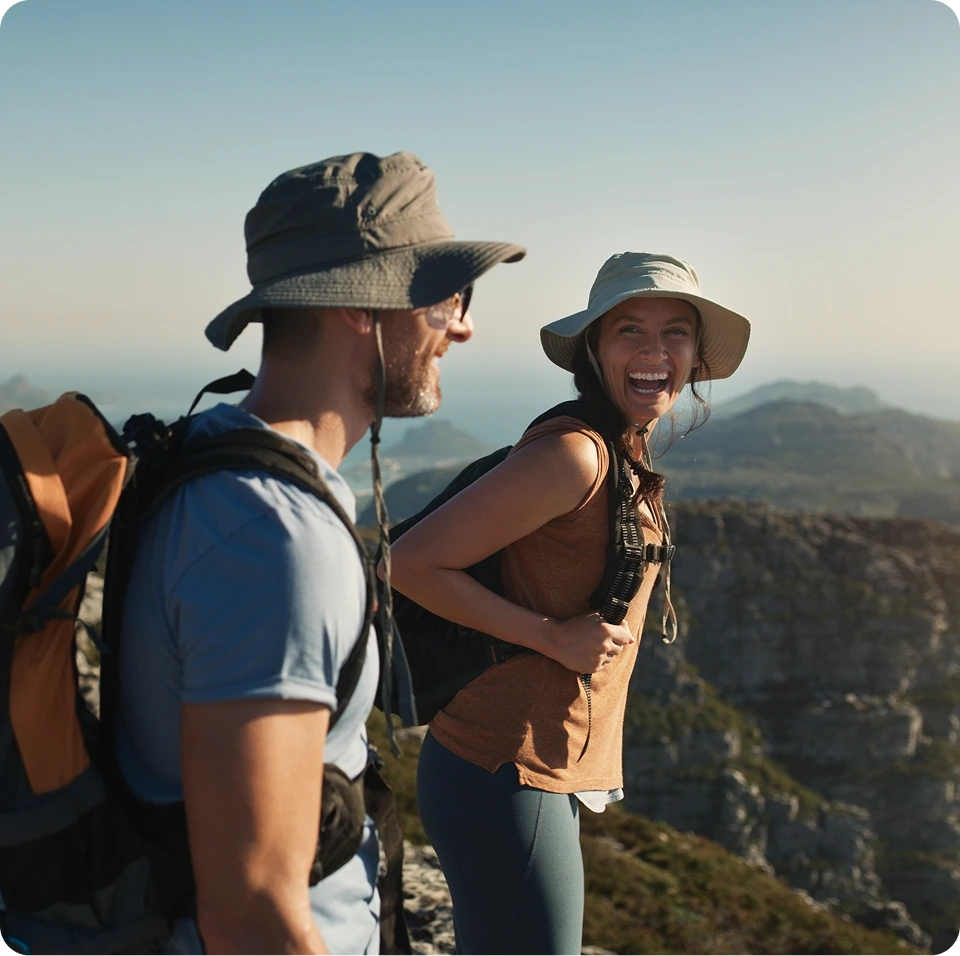 Two hikers smiling on mountain overlook with valley landscape in background
