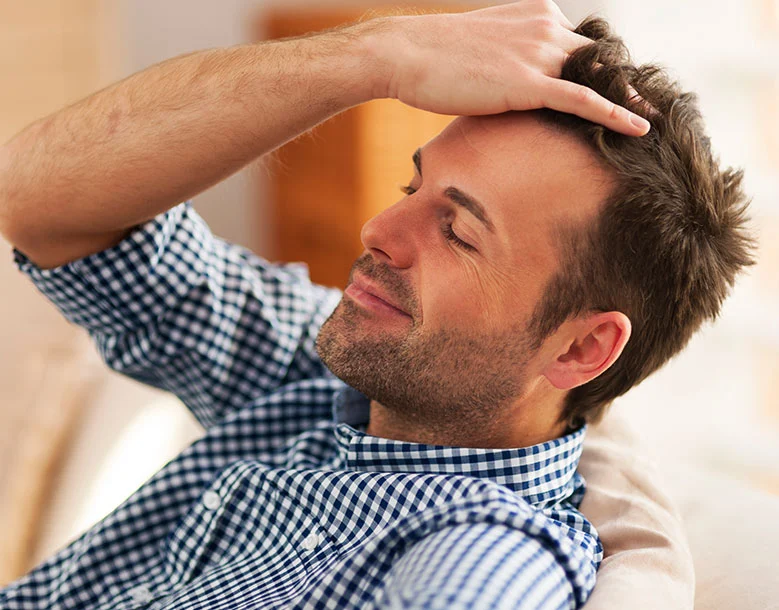 Man examining hairline and hair with hand in profile view