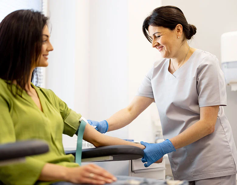 Laboratory technician drawing blood from patient's arm using a needle and collection tube