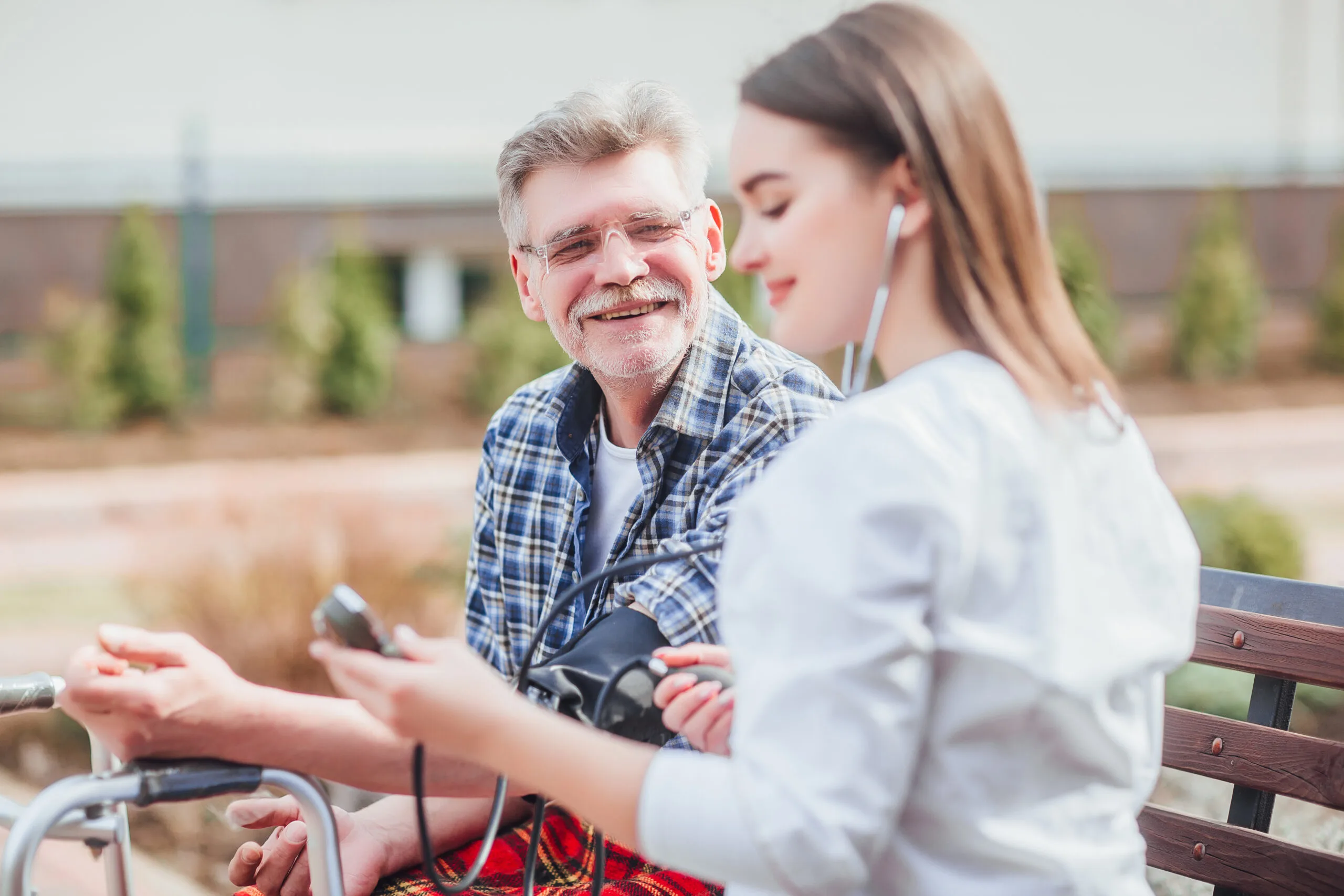 Nurse checking pulse on older man's wrist in outdoor clinic garden setting