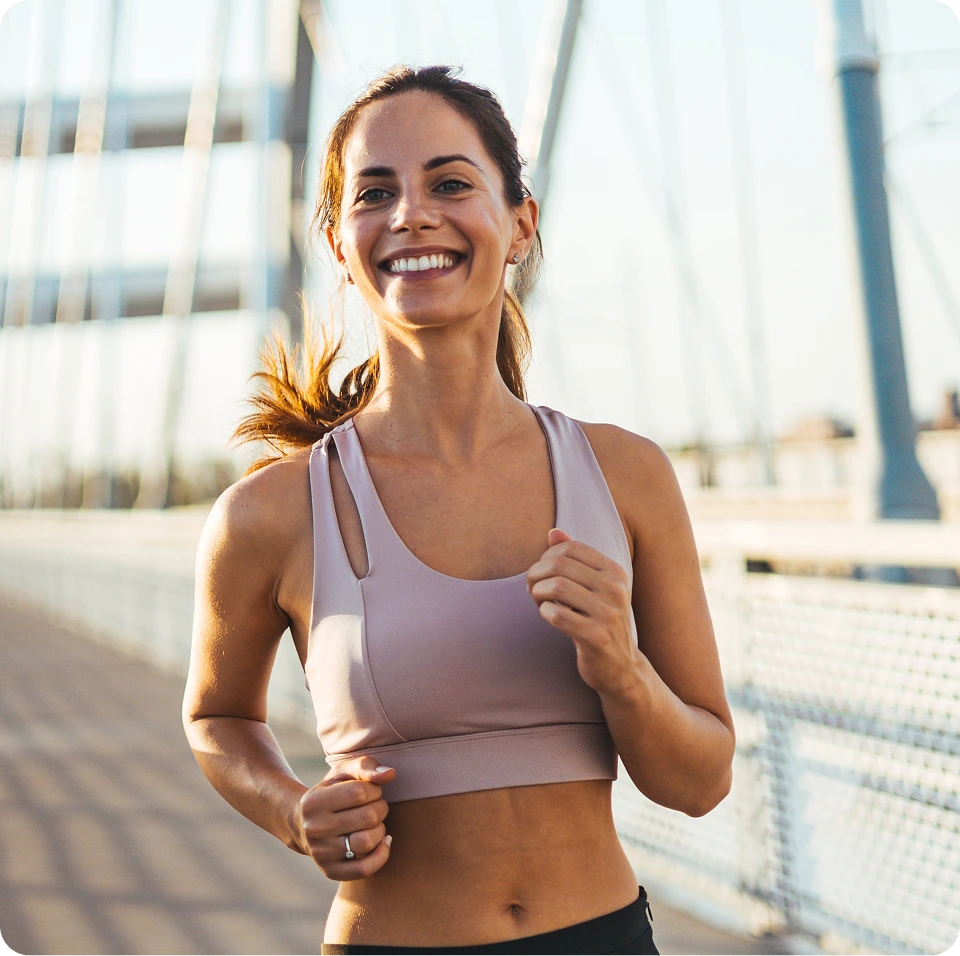 Woman in purple sports top jogging outdoors with modern buildings in background