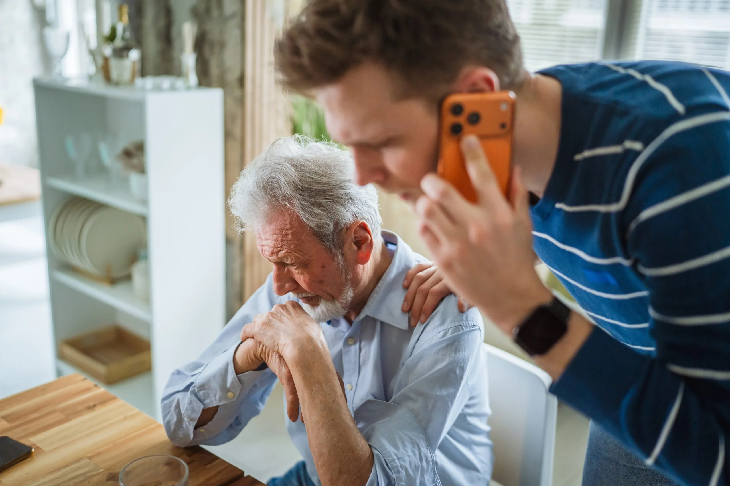 Adult son taking photo of elderly father's wrist pain on smartphone at home