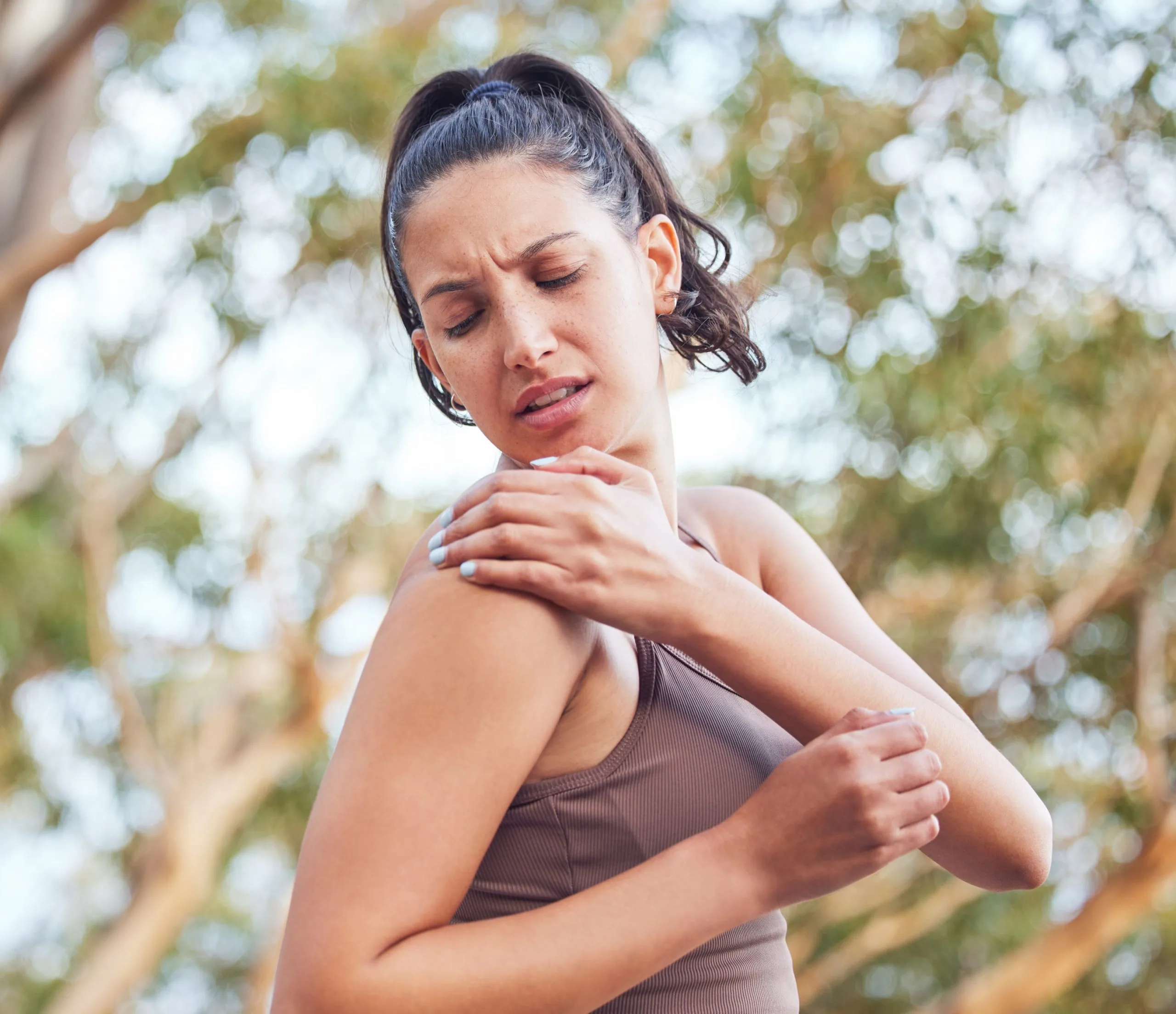 Woman holding her shoulder in pain outdoors