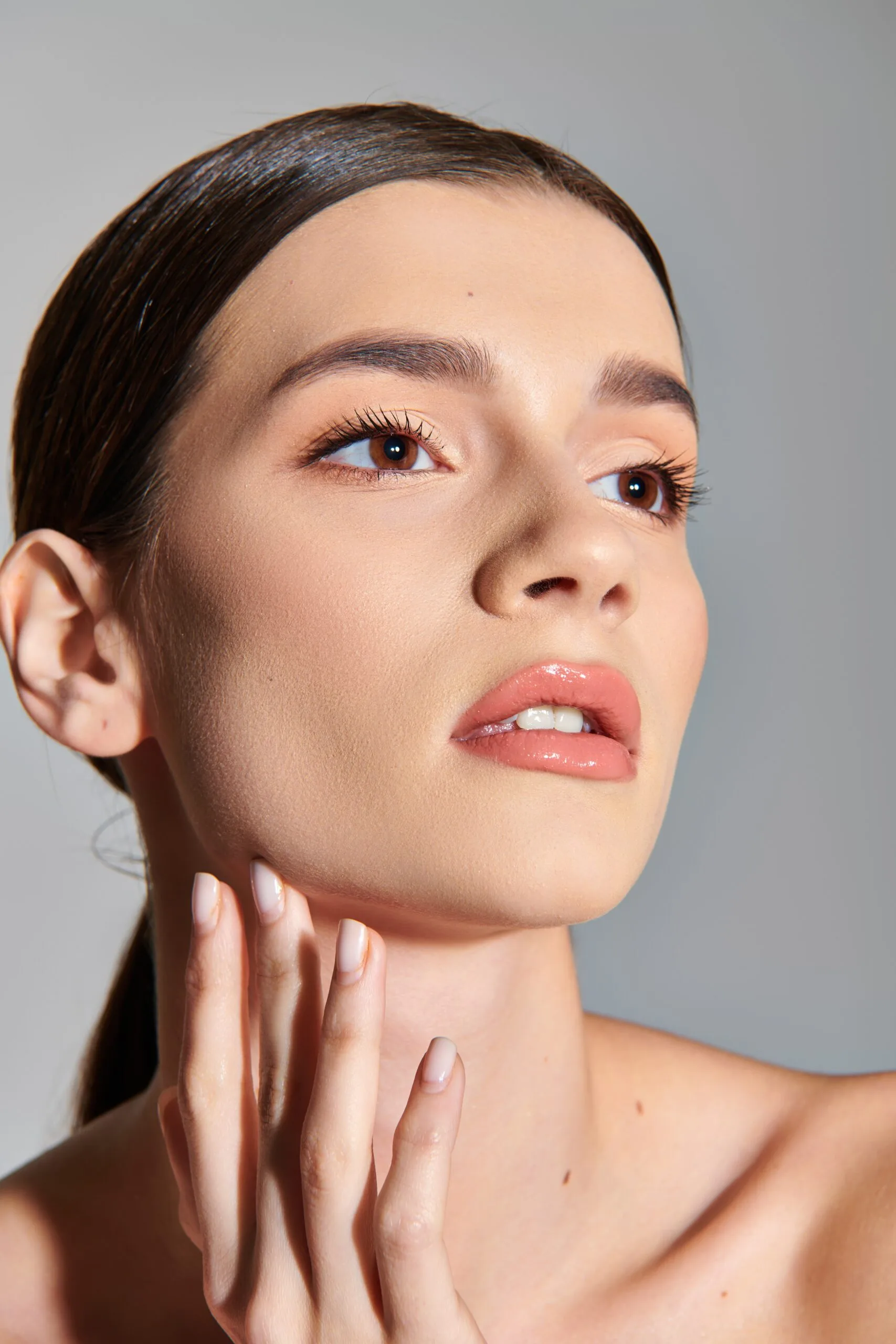 Woman with smooth, glowing skin touching her cheek after dermaplaning treatment