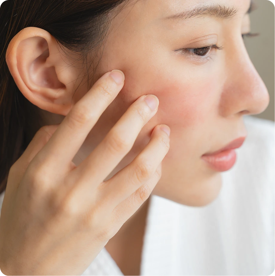 Person touching cheek with fingers, showing skin texture and complexion