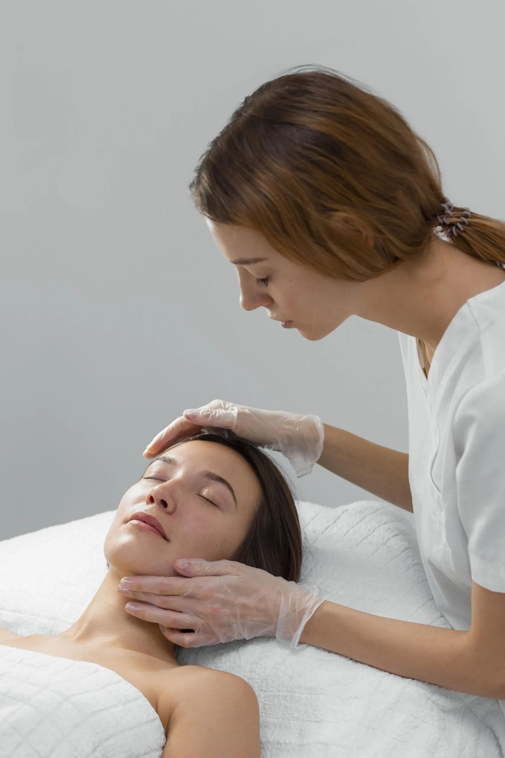 Aesthetician performing a Glo2Facial treatment on a relaxed patient lying on a treatment bed