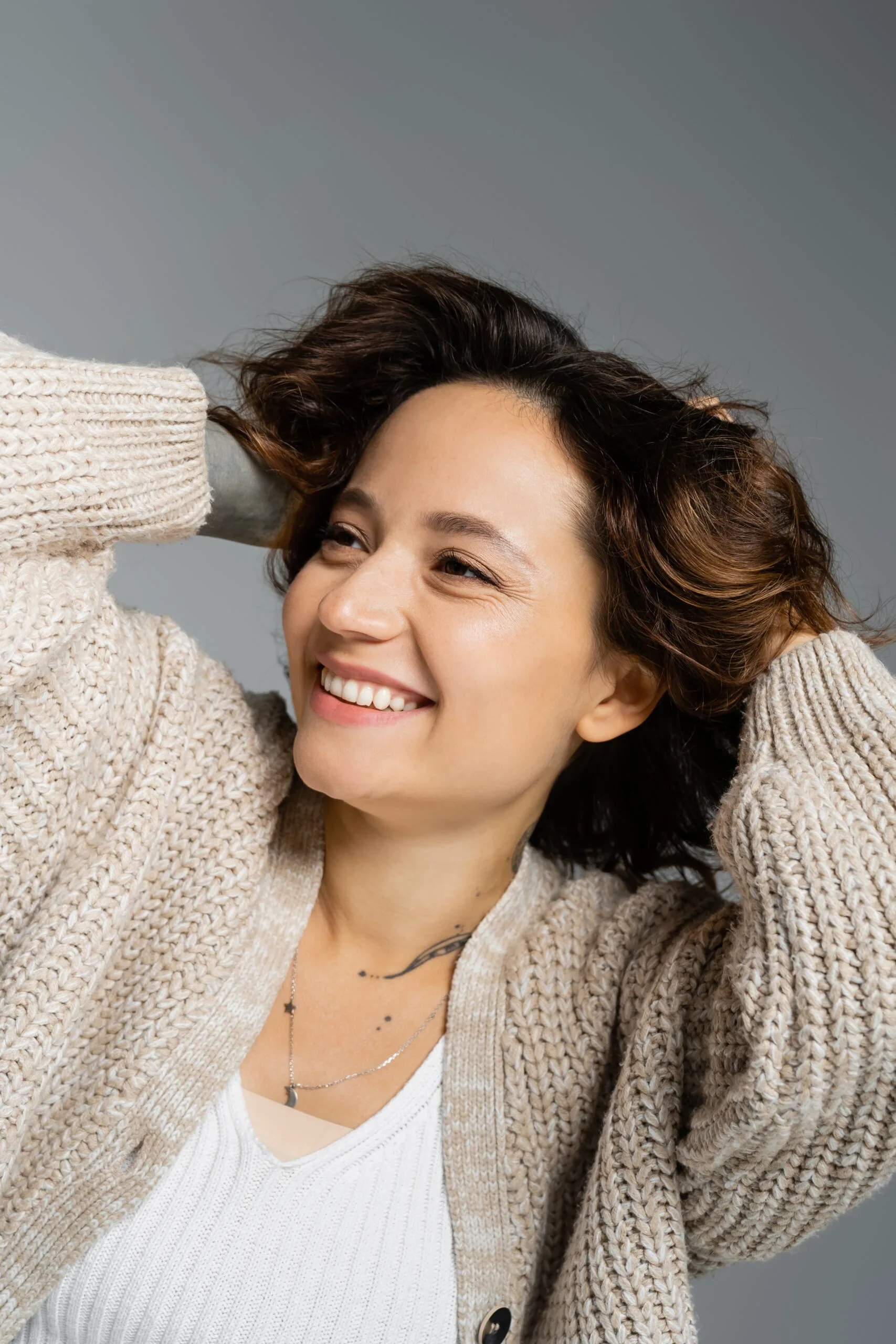 Woman with smooth underarms smiling with hands behind her head