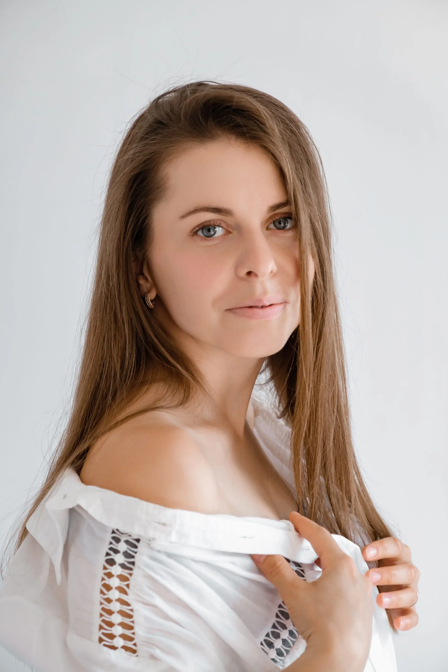 Woman with brown hair and fair complexion, looking toward camera against neutral background