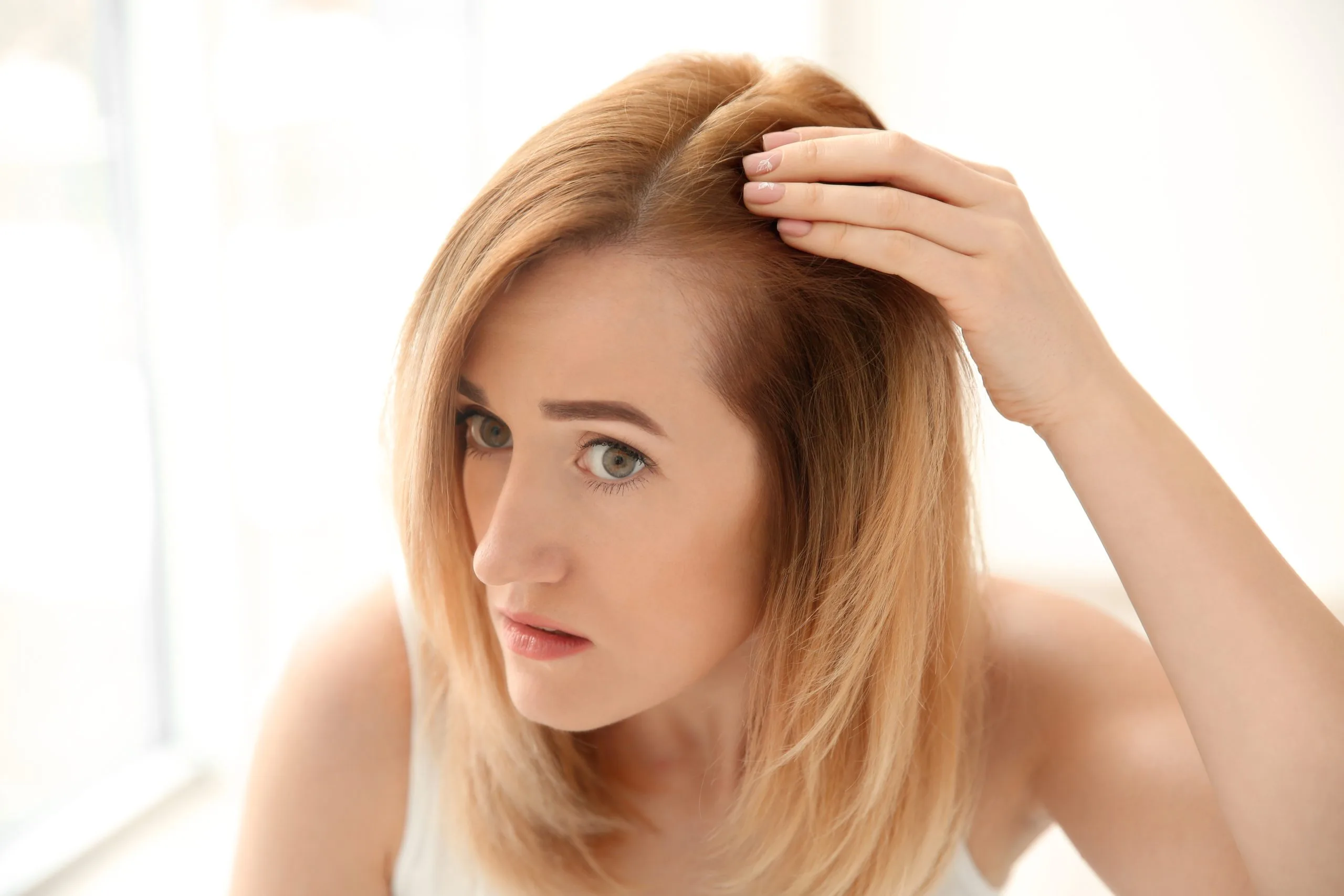 Woman touching her scalp examining hair in bright natural light