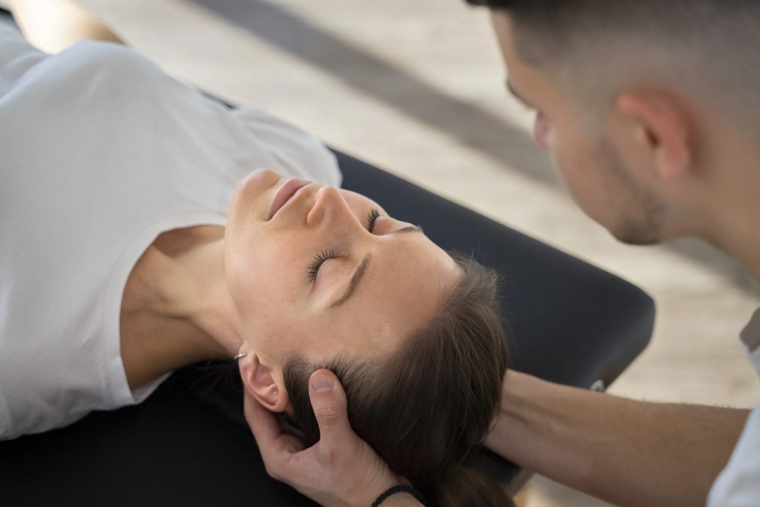 Therapist performing neck and head manipulation on patient during treatment session