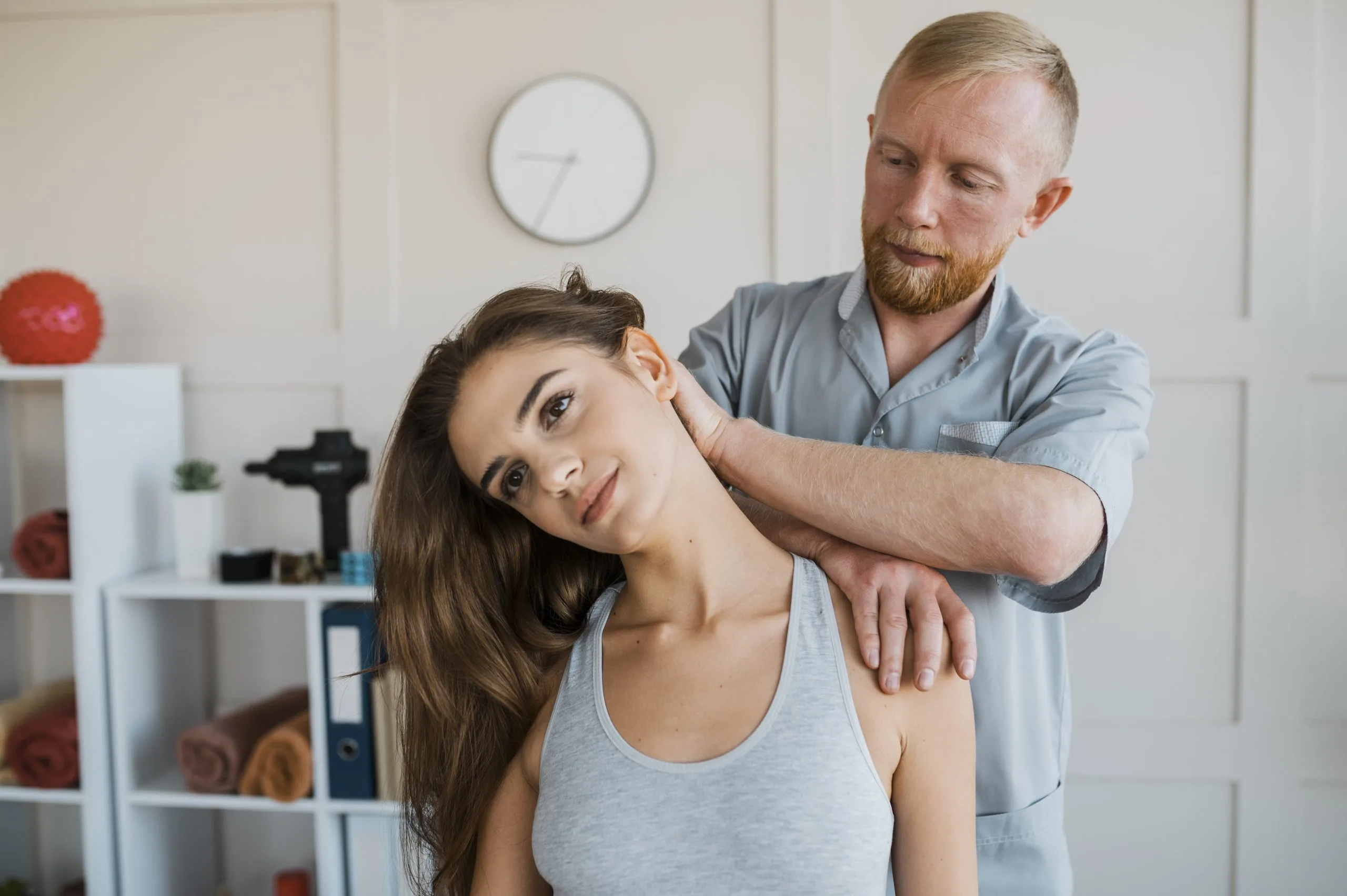 Physiotherapist performing neck stretching treatment on female patient in clinic