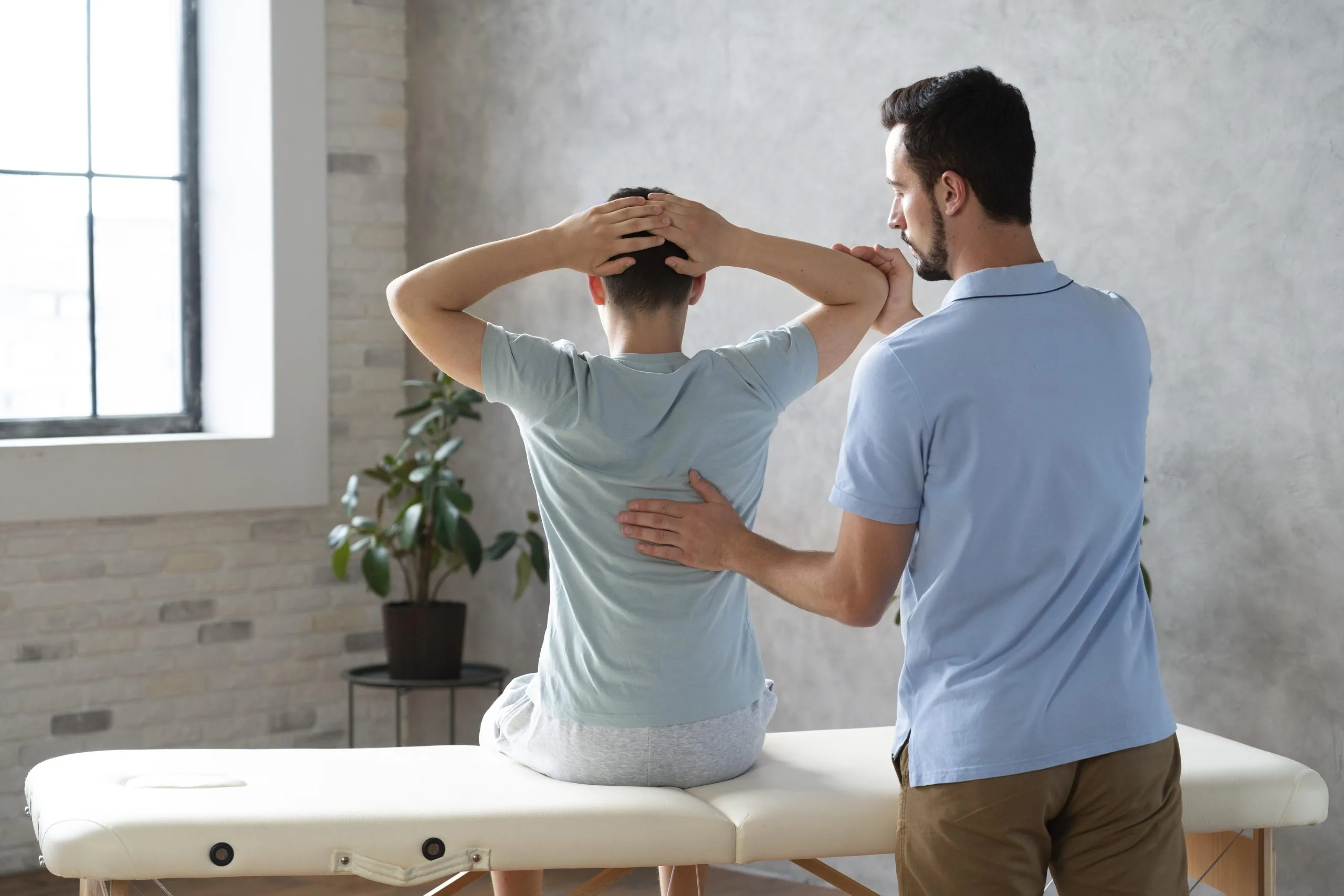 Physiotherapist guiding patient through neck and shoulder mobility exercise on treatment table